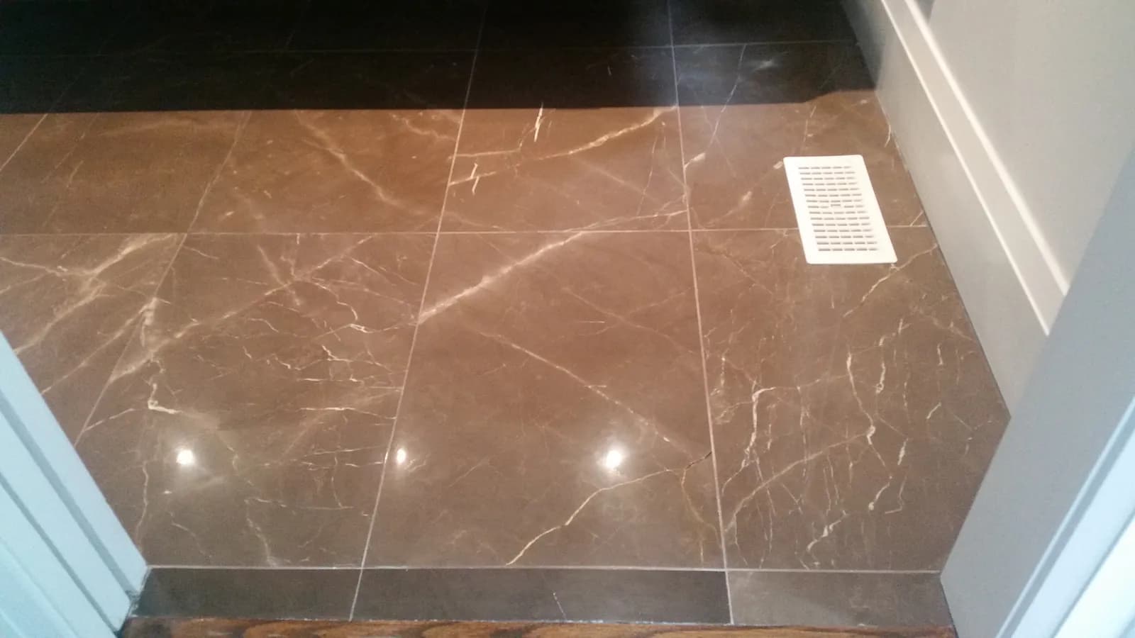 Polished brown marble bathroom floor with white veining