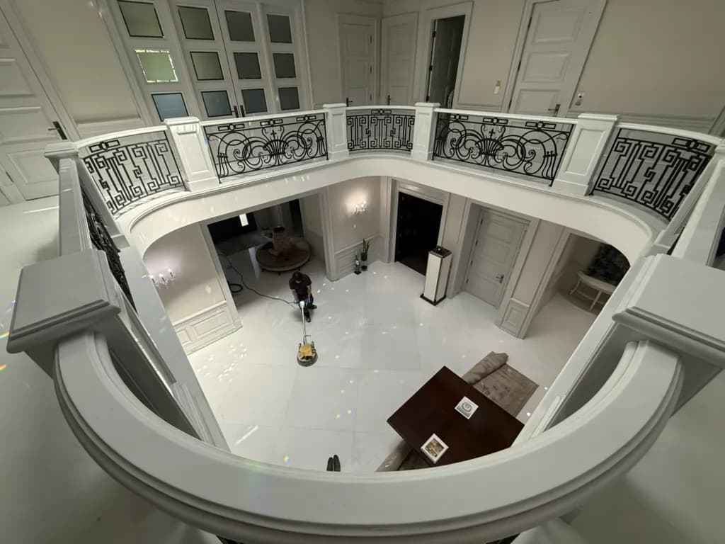 Technician polishing a white marble floor in a two-storey foyer