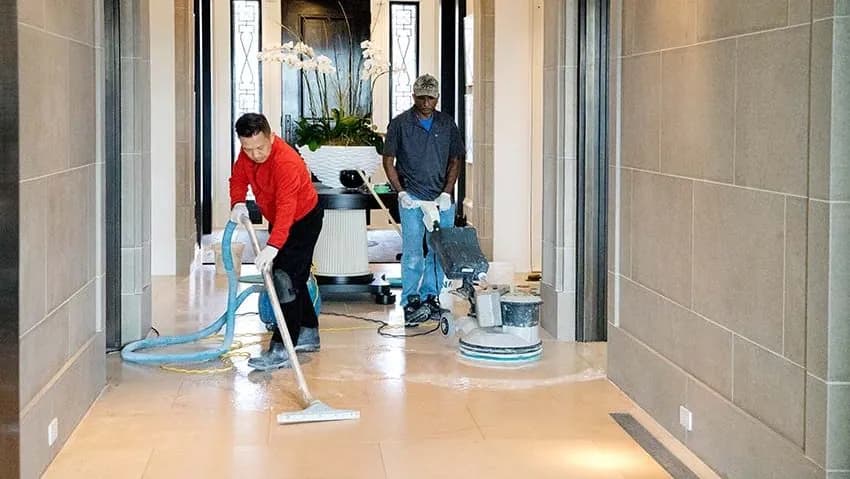 Two technicians cleaning and polishing a hallway floor