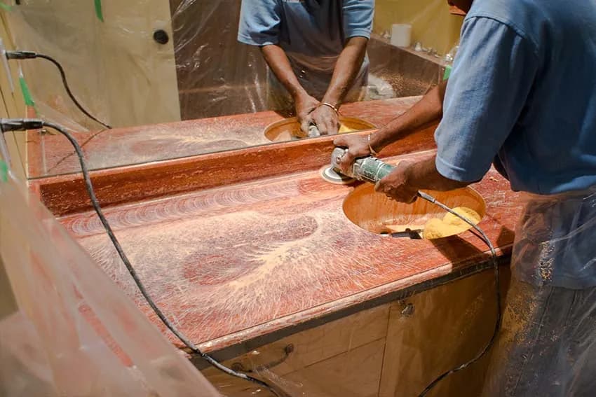 Two technicians grinding a red marble vanity top