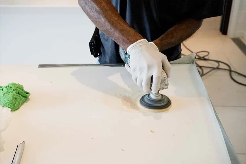 Technician polishing the edge of a white stone countertop