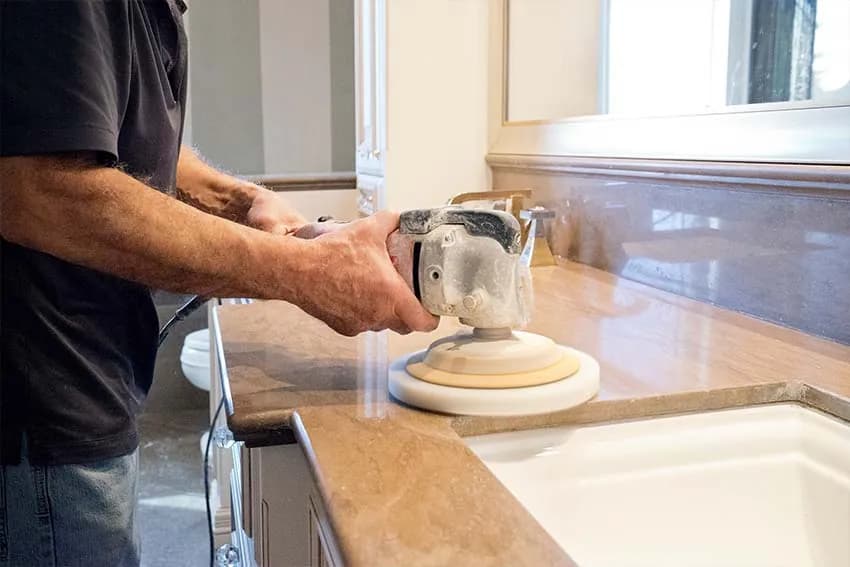 Technician polishing a stone vanity top beside the sink