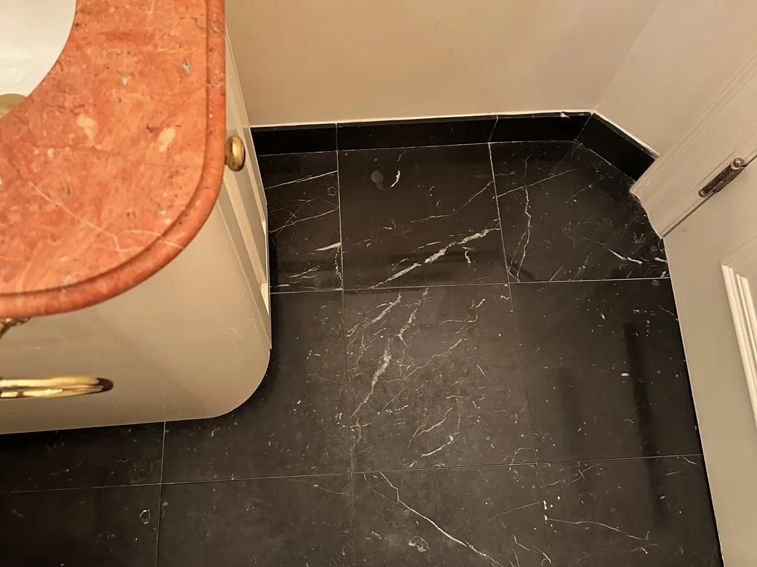 Worn black marble powder room floor, before