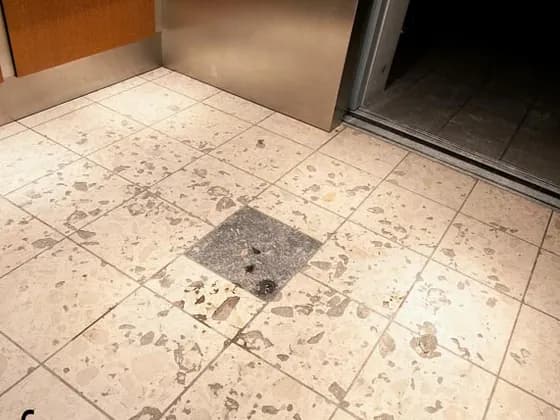 Stained agglomerate marble elevator lobby before restoration