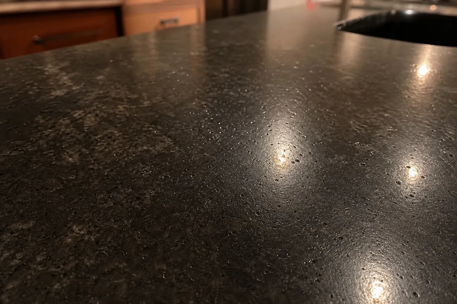 Black granite countertop with pinhead pits catching the light