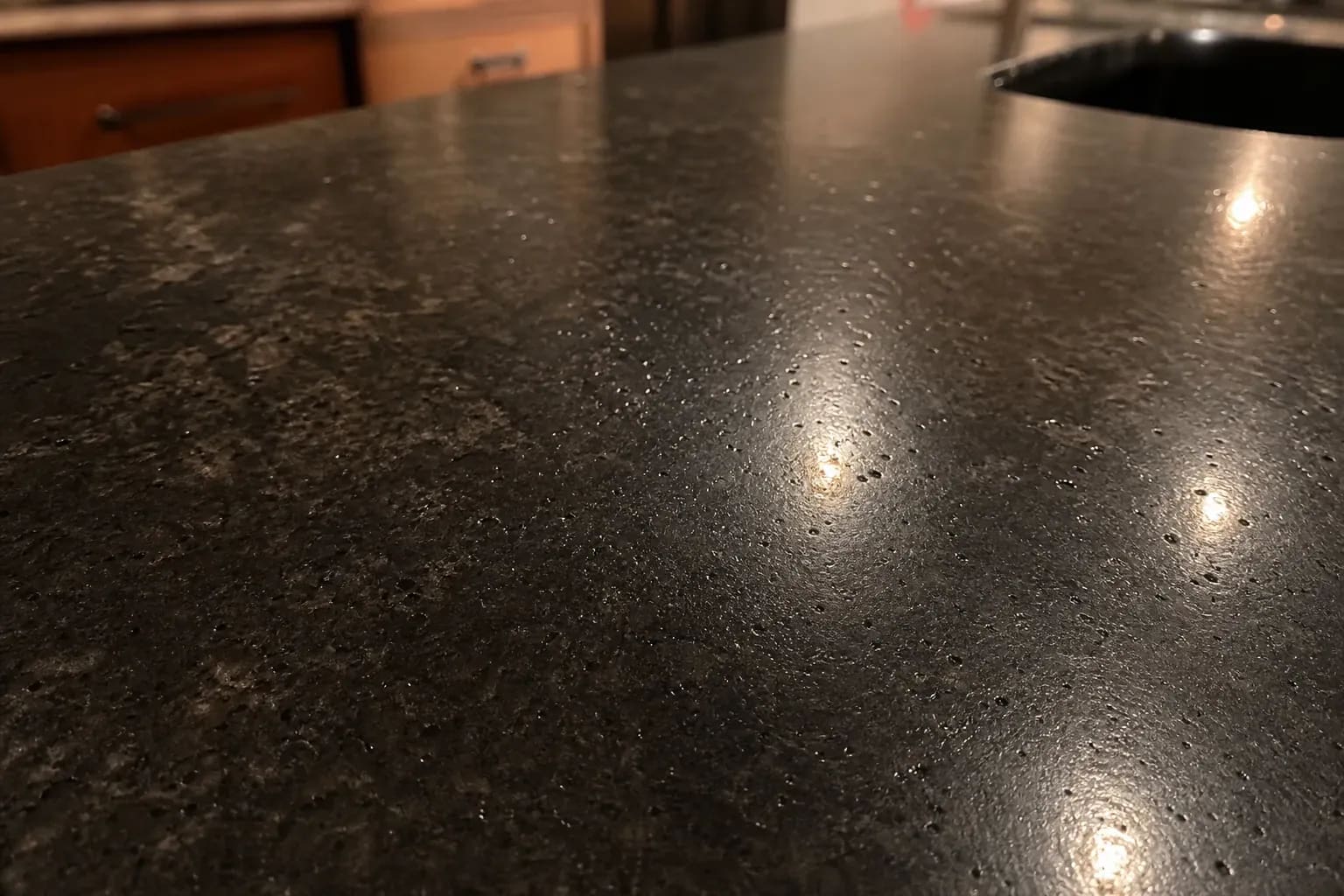 Black granite countertop with pinhead pits catching the light
